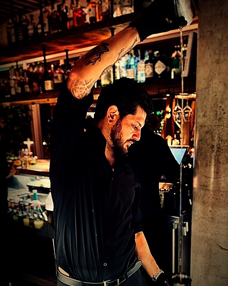 Andres Caro throwing a cocktail behind the bar