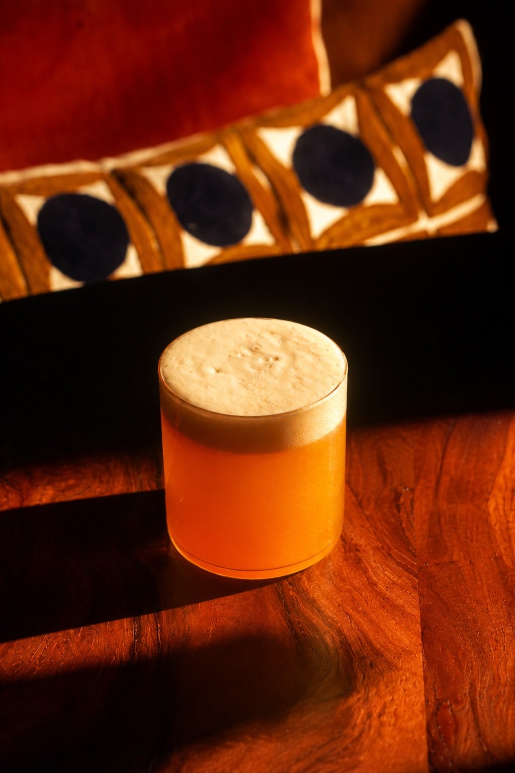 Coconut Aperol sour with silky egg white foam in golden light